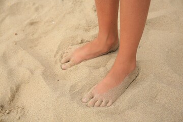 Fototapeta na wymiar Little girl standing on sandy beach, closeup