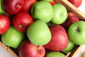 Wooden crate with ripe red and green apples on white table, top view