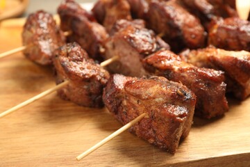 Delicious shish kebabs on wooden board, closeup