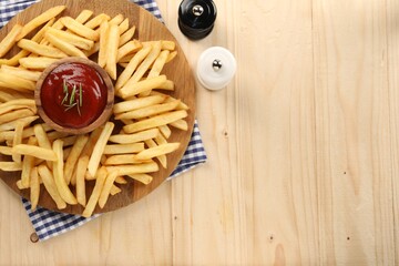 Delicious french fries served with ketchup on wooden table, flat lay. Space for text