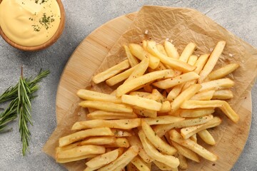 Delicious french fries served with sauce on grey table, flat lay