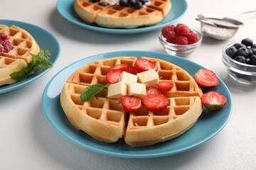 Tasty Belgian waffles with fresh berries served on white table, closeup