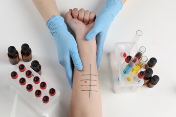 Patient undergoing skin allergy test at light table in clinic, top view