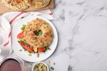 Tasty bagel with salmon and tomatoes on white marble table, flat lay. Space for text