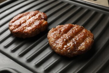 Delicious hamburger patties on electric grill, closeup