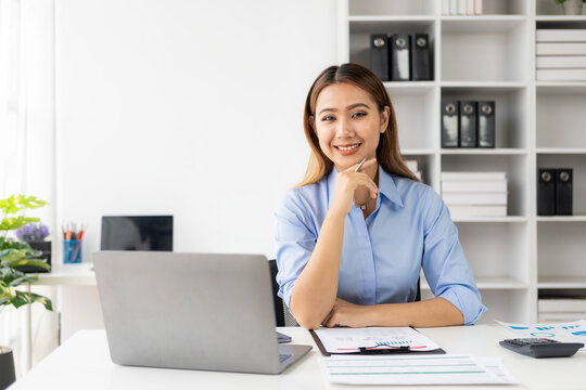 Cheerful businesswoman working with laptop, female office worker smiling charmingly. Work with financial documents to analyze company financial data.