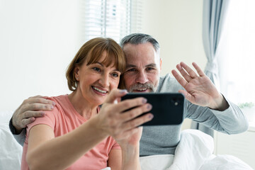 Caucasian senior couple video call with family in bedroom in house. 