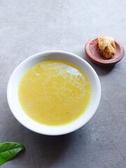 bowl of soup. Homemade chicken stock in a bowl on a gray background. soup. chicken gravy. yellow sauce. ingredients. delicious. Vertical shot