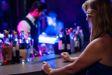 Caucasian profession bartender making a cocktail for women at a bar. 