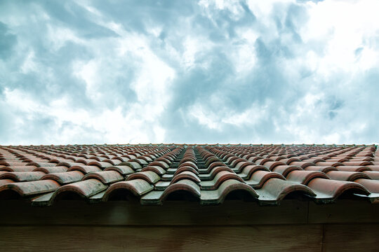 the shape of the roof of the house is made of red tiles with a bright, cloudy sky in the background