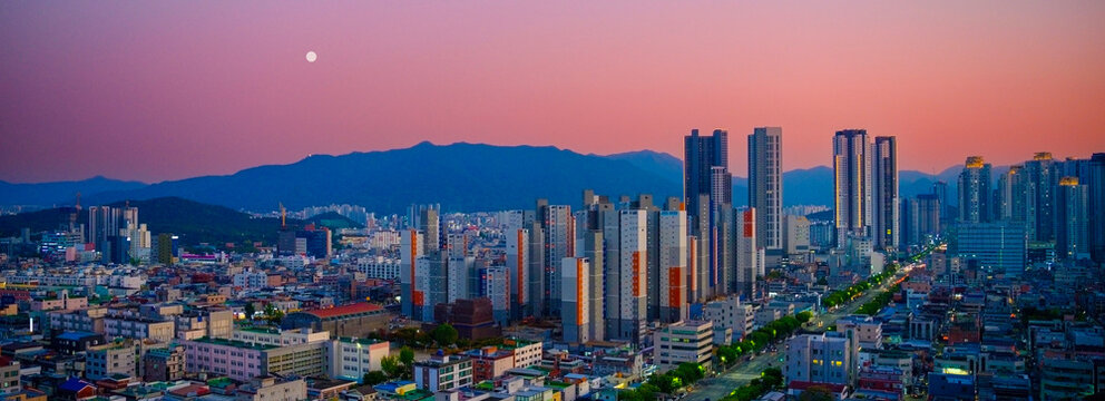 Moonrise over Daegu City skyline in South Korea, Apsan mountain and pink sky over the skyscrapers, office and residential buildings. 