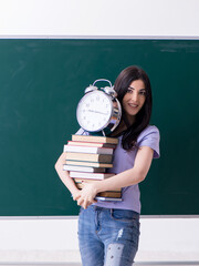 Young female teacher student in front of green board