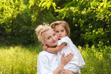 Portrait of beautiful mother with her cute daughter outdoors