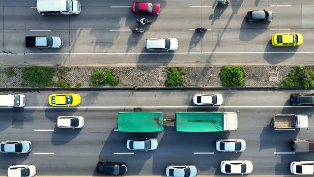 An intercity motorway, gridlocked with cars, stands still amidst a chaotic traffic jam. A drone captures the frustration from above. Traffic and vehicle concept. Road and cars background. Thailand.
