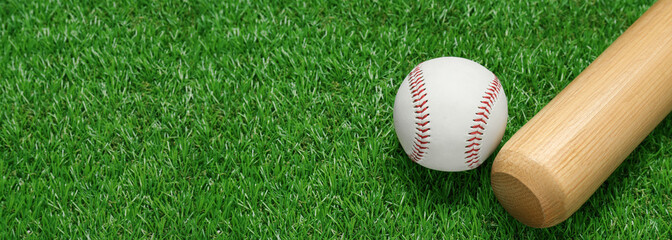 Wooden baseball bat and ball on green grass, space for text. Banner design