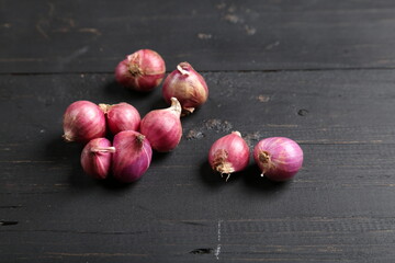 An Array of Unpeeled Red Onions Resting on a Rustic Black Wooden Board