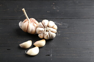 Several cloves of garlic placed on a black rustic wooden board.