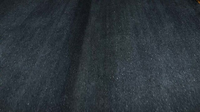 In the tender embrace of dawn, the virgin asphalt road whispers beneath the wheels of a moving car, a symphony of progress painted with tire imprints. Car and road background. POV view.
