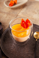 A glass of traditional Italian dessert panna cotta with peaches, vertical photo