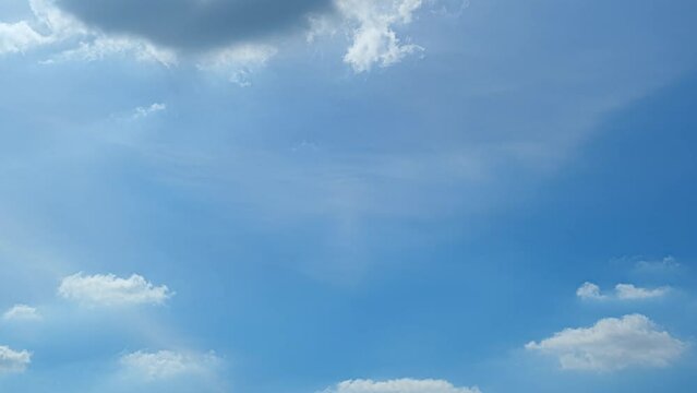 The blue sky transforms, orchestrating a breathtaking timelapse spectacle. Clouds form and disperse, a celestial ballet against the azure backdrop, creating a mesmerizing visual symphony. Time lapse.
