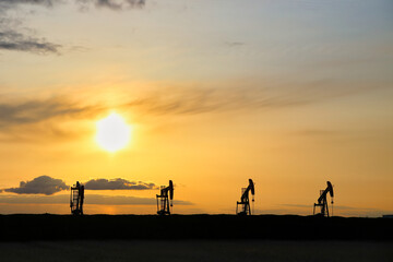 A row of oil pumpjacks at sunset