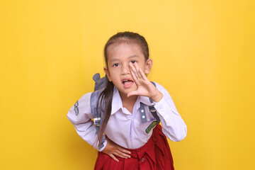 Cheerful Asian schoolgirl in uniform wearing backpack and shout to front making announcement gesture