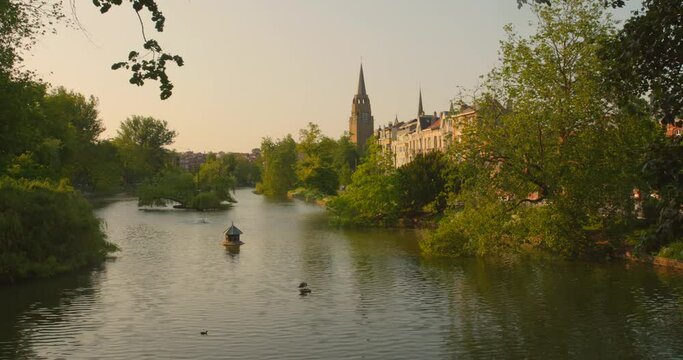 High angle shot over Ixelles Ponds in Brussels, Belgium with an old church in the background at golden hour.