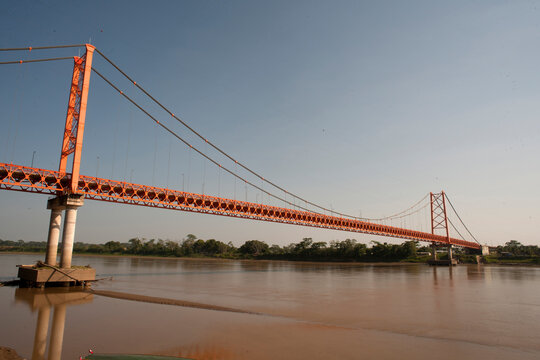 View of a boat dock on the Madre de Dios River, with the Presidente Guillermo Billinghurst suspension bridge Puerto Maldonado, Peru.