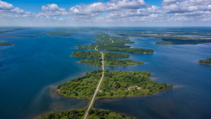 Aerial photo of Long Sault Parkway scenic route crossing Thousand Islands archipelago in the Saint Lawrence River near Cornwall, South Stormont, Ontario, Canada. Photo taken by drone in June 2022. - obrazy, fototapety, plakaty