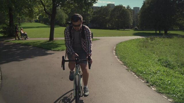 Cyclist uses smartphone application on handlebar of his bicycle to navigate while cycling in park in Germany. Man planning route using GPS navigation application in mobile phone while riding a cycle. 