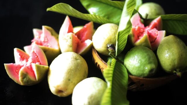 Cinematic dolly shot of ripe red guava fruit on a black shiny glossy wooden surface. Desi amrud or jamrukh (Psidium guajava) on a wooden surface. High-quality HD footage.