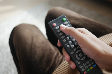 close up of women hand holding tv remote.