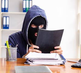 Male thief in balaclava in the office