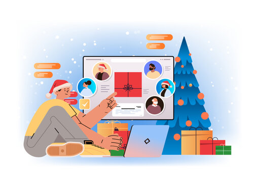 man in santa hat chatting with mix race friends on laptop screen near decorated christmas tree and gift boxes social media communication