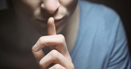 Woman gesturing to be quiet with a finger before her mouth.