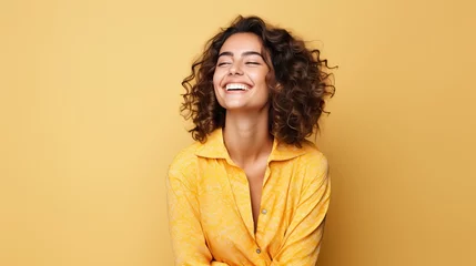 Foto op Plexiglas Portrait of a cheerful young woman wearing yellow shirt standing isolated over yellow background, looking at camera, posing © Kowit