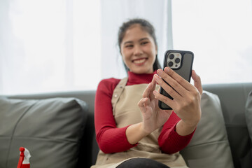 The housekeeper is relaxing after cleaning the house, Playing on the phone on the sofa, Watch videos on your smartphone after cleaning the house, relaxing idea.