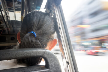 A woman watches the street from a moving city bus
