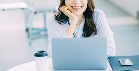 ノートパソコンを使う笑顔の日本人女性ビジネスマン