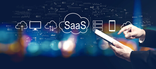 SaaS - software as a service concept with businessman using a tablet computer at night