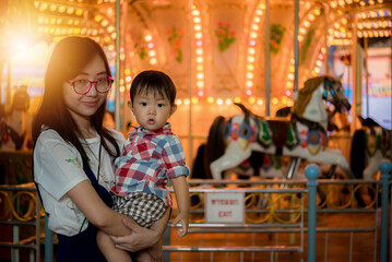 Portrait of happy mother and baby boy in amusement park night