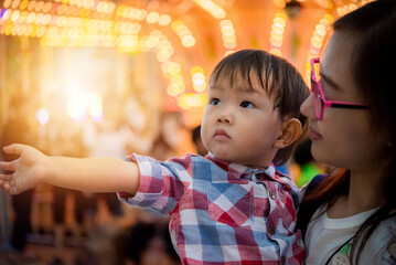 Portrait of happy mother and baby boy in amusement park night