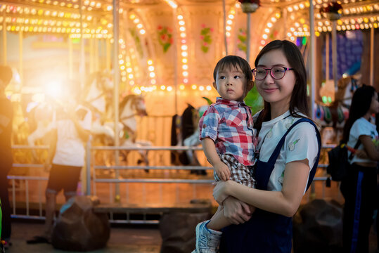 Portrait of happy mother and baby boy in amusement park night