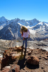 Naklejka premium The girl with her back to the camera looking at the tall mountains in Elbrus