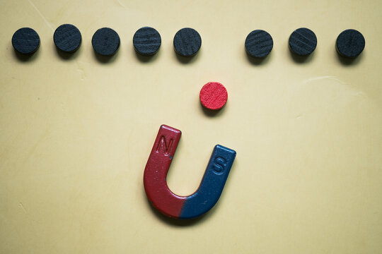Magnet attracting the one red circle wood block from a row black, attract toxic people get out organization