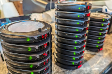 Stacks of wireless restaurant pager, buzzers or beepers at the counter of a cafe. An Electronic Restaurant Guest Paging System.