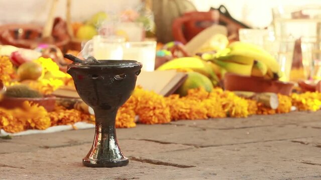 day of dead celebration. Horizontal video of an altar decorated with colorful yellow cempazuchitl yellow flower, banana, glass of water and burning incense in a traditional copal made of clay