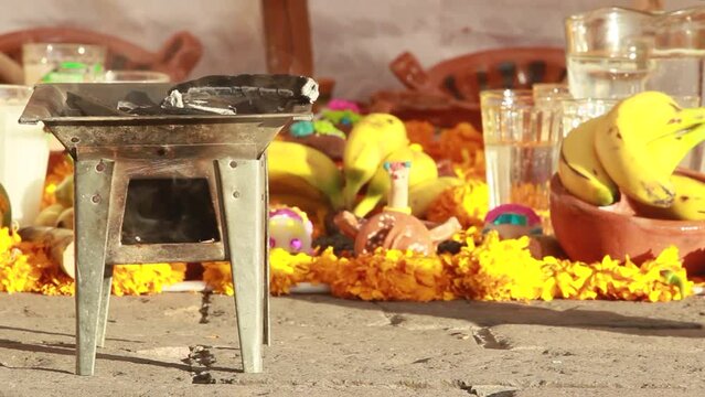 day of dead celebration. Horizontal video of an altar decorated with colorful yellow cempazuchitl yellow flower, banana, sugar candies in shape of a skull, glass of water and burning incense in a copa