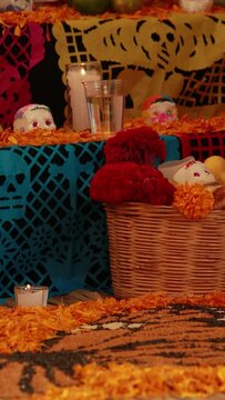 day of dead celebration. vertical video of an altar or ofrenda decorated with colorful yellow cempazuchitl yellow flower, banana, sugar candies in shape of a skull, glass of water