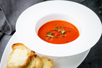 borscht with herbs in a white plate with pieces of bread, side view